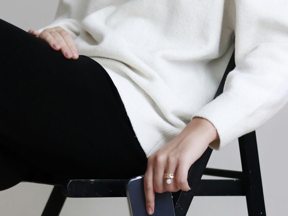 The personal shopper listening, a hand resting on her knee · stand-in frame